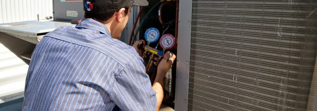HVAC technician servicing a condenser unit in Bellefontaine